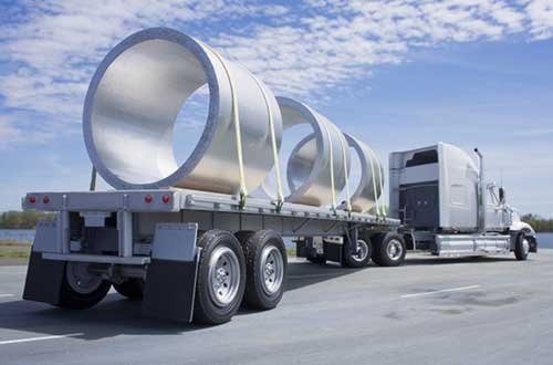 Flatbed truck carrying steel beams on highway in USA representing flatbed dispatch service USA logistics