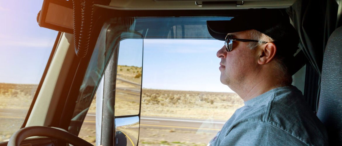 Owner operator truck driver standing near truck on highway showing stress and loss of control in no forced dispatch situation