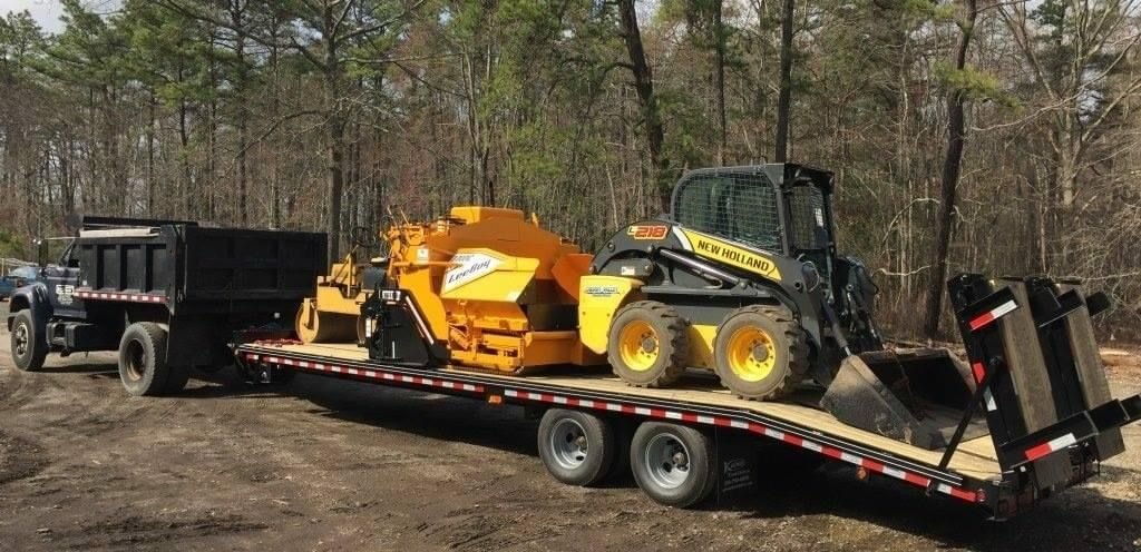 Hotshot freight carrying construction equipment on a flatbed trailer